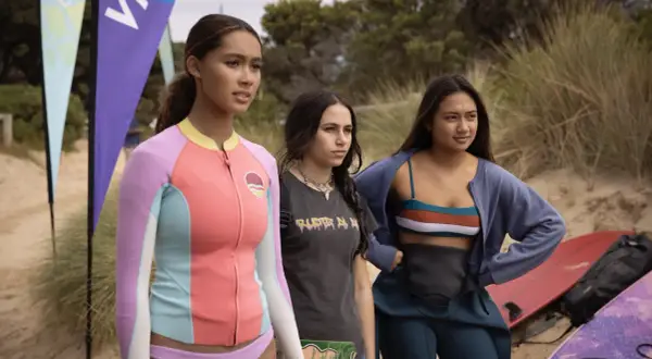 Drei junge Frauen stehen am Strand, bereit für die Wellen. Savannah La Rain und ihre Freundinnen warten auf den perfekten Surf.