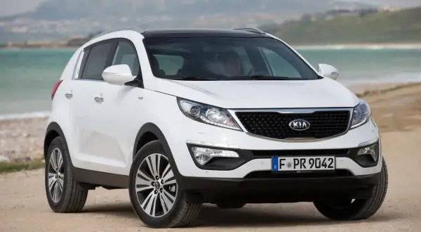 Biały Kia Sportage 2014 na plaży, gotowy na przygodę nad morzem.