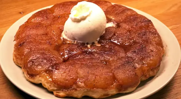 En gyllene tarte tatin med en kula vaniljglass som smälter över de karamelliserade äpplena.