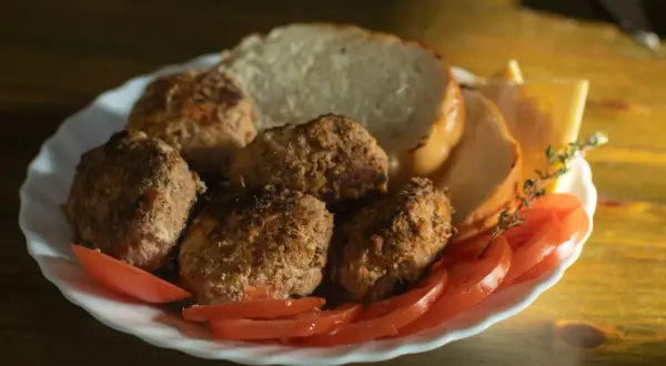 Talerz z kotletami mielonymi, kromkami chleba, pomidorami i serem. Idealny na szybki obiad, choć warto sprawdzić kotlet mielony kcal.