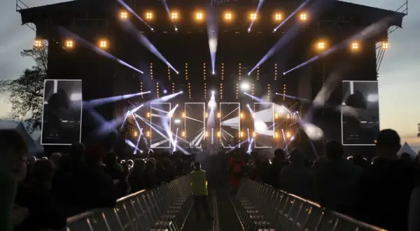 Jarocin Festival rozświetlony tysiącami świateł. Tłum czeka na koncert, a na scenie widać artystów.