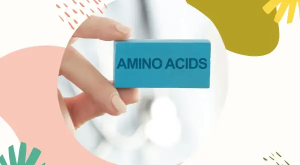 Dłoń trzyma niebieski klocek z napisem "AMINO ACIDS". Kluczowe składniki w kosmetykach dla zdrowej skóry.
