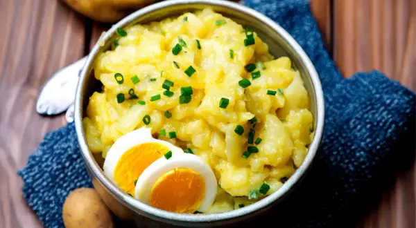 Omas Kartoffelsalat, cremig und herzhaft, garniert mit Schnittlauch und gekochtem Ei. Ein Klassiker, der immer schmeckt.