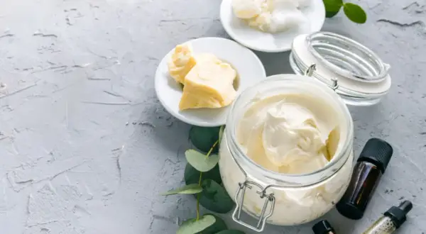 Zutaten für **Body Butter selber machen**: Kakaobutter, Sheabutter, Kokosöl und ätherische Öle. Cremige Textur in einem Glasbehälter.