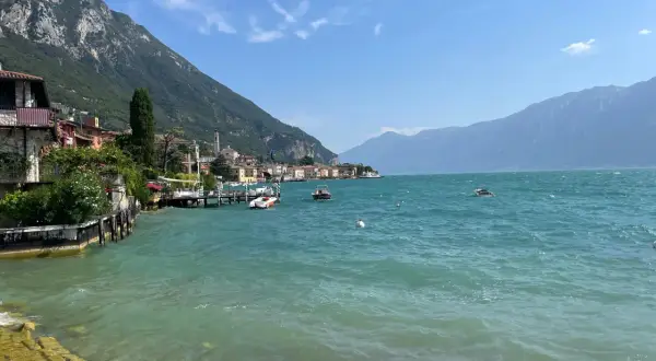Vista sul lago con montagne sullo sfondo, barche e case colorate. Un vero gargnano geheimtipp.