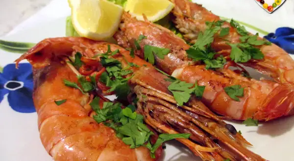 Assiette de gambas grillées, garnie de persil frais et de quartiers de citron. Une belle idée pour une recette gambas légère et savoureuse.