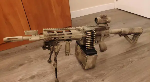 Réplica de airsoft con camuflaje personalizado. El detalle de pintar replica airsoft es impresionante, con un cargador de cinta y mira holográfica.