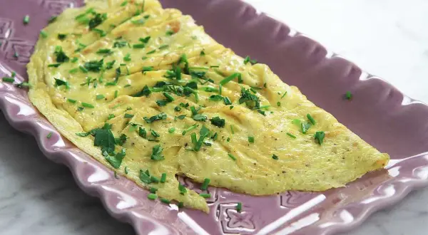 En perfekt vikt omelett med gräslök, redo att serveras. Ett enkelt omelett recept för en snabb och god måltid.