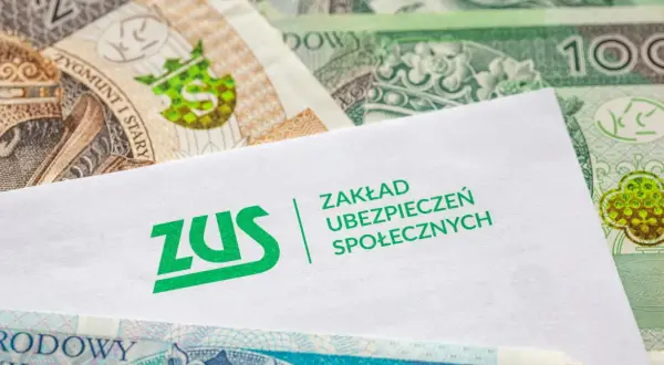 Koperta ZUS na tle polskich banknotów. Dokumenty dotyczące zasiłku chorobowego i pieniędzy.