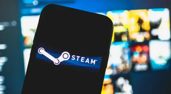 Smartfon z logo Steam na ekranie, w tle rozmyte okładki gier. Czekam na oczekujące środki Steam.