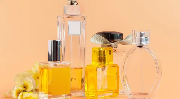 Kilka eleganckich flakonów z perfumami, w tym jeden z żółtym płynem i kwiatową ozdobą. Woda toaletowa ile ma procent? To zależy od jej stężenia.