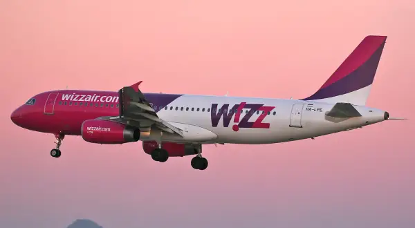 Samolot Wizz Air z różowym dziobem i fioletowym ogonem w locie. Wizz priority to komfort podróży.