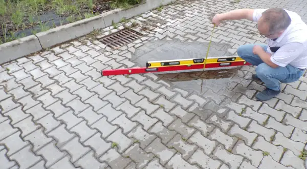 Mężczyzna sprawdza poziom wody na chodniku z kostki brukowej.