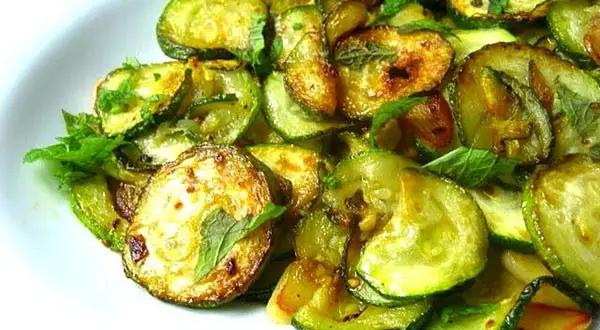 Zucchine alla scapece ricetta napoletana: fette di zucchine fritte e marinate con menta fresca, un contorno saporito e profumato.