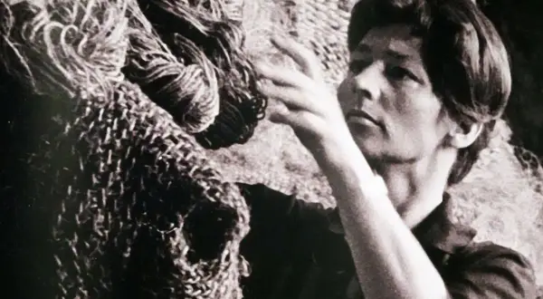 Magdalena Abakanowicz dotyka swojej monumentalnej rzeźby z włókien, tworząc dzieło sztuki.