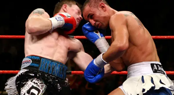 Two boxers exchange powerful boxing punches in the ring. One fighter lands a blow to the head, while the other attempts to counter.