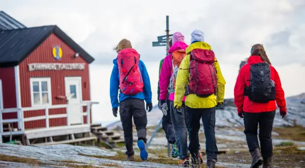 Vandringsgrupp närmar sig STF Sylarnas fjällstation. Vackert höstlandskap med molnig himmel.
