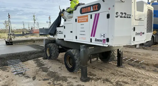 Maszyna do betonu Dromaxx S-22EZ pracuje nad wylewaniem nawierzchni. Widać zbrojenie, które będzie częścią stóp fundamentowych.