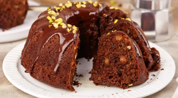 Puszysta babka na oleju, polana czekoladą i posypana pistacjami, kusi swoim wyglądem. Idealna na deser.