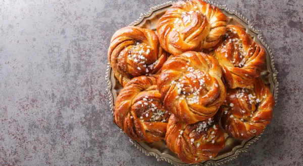 En bricka med nybakade kanelbullar, perfekta att baka i varmluftsugn. Strösslade med pärlsocker.