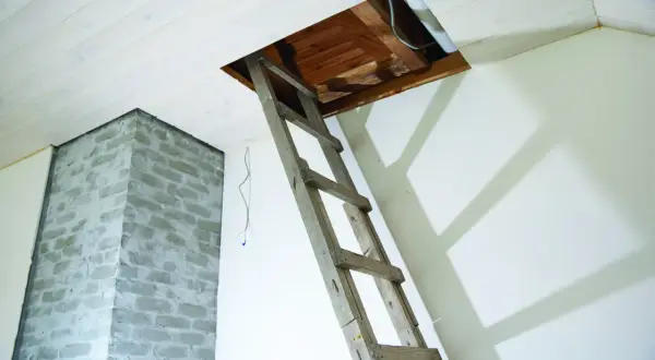Drewniana drabina prowadzi do otwartego strychu. Czy wymiana schodów w starym domu wymaga pozwolenie na budowę czy zgłoszenie?