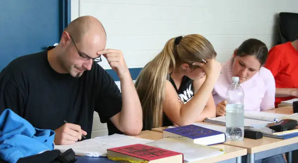 Konzentrierte Studierende beim lateinischen Fernstudium, vertieft in ihre Unterlagen.
