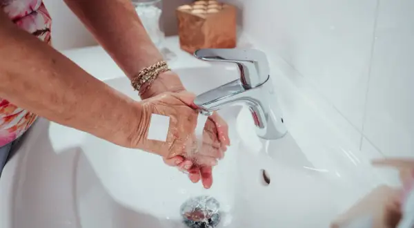 Hände waschen mit Pflaster auf einer kleinen wunde. Ein Hausmittel zum wasserdicht abdecken ist hier zu sehen.