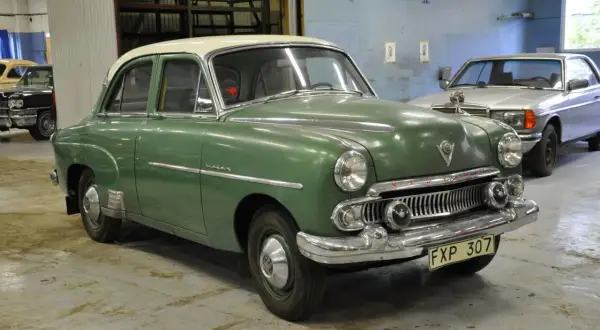 Grön Vauxhall Velox med vitt tak står i ett garage. En silverfärgad bil syns i bakgrunden.