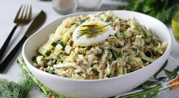 Lekka sałatka z tuńczykiem, jajkiem i ogórkiem, udekorowana koperkiem. Idealna na szybki lunch.
