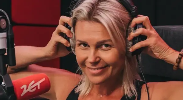Agnieszka Kołodziejska, w wieku około 40 lat, z uśmiechem na twarzy zakłada słuchawki w studiu radiowym.