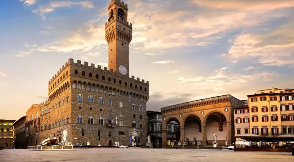 Il maestoso Palazzo Vecchio domina Piazza della Signoria, con la sua torre imponente che svetta nel cielo al tramonto.