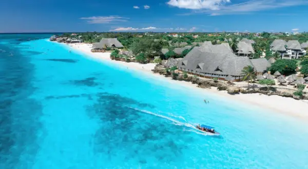 Idealny dzień, kiedy na Zanzibar. Turkusowa woda, biała plaża i łódź z turystami.