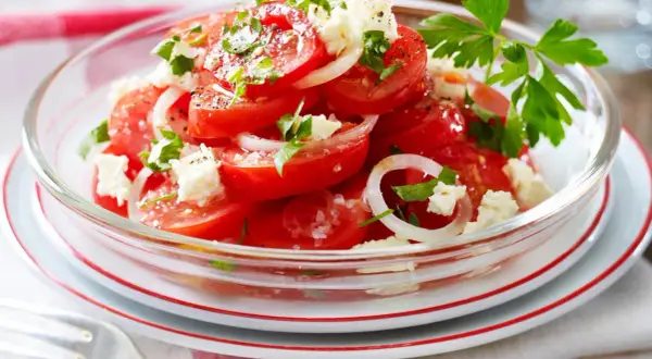 Frischer tomatensalat mit feta, Zwiebeln und Petersilie, garniert mit Pfeffer und Salz. Ein leichter Genuss.