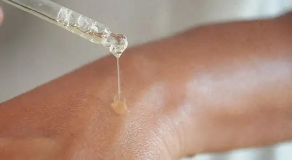Kropla serum z niacynamidem 5% spada na skórę, nawilżając ją i odżywiając.