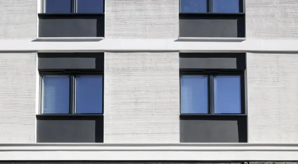 Moderne Fassade mit Klinker und Putz. Fenster mit dunklen Rahmen und blauen Scheiben.