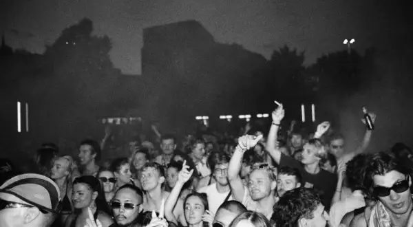 Folla in delirio a un concerto, con mani alzate e luci soffuse. Marco festa dj fa ballare tutti.