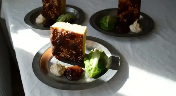 Enkel lyxig middag: bitar av rostat bröd med sesamfrön, serverade med sallad, en klick krämig röra och sylt på metalltallrikar.