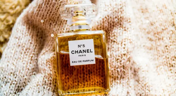 Elegancka butelka Chanel N°5 Eau de Parfum na miękkim, błyszczącym swetrze.