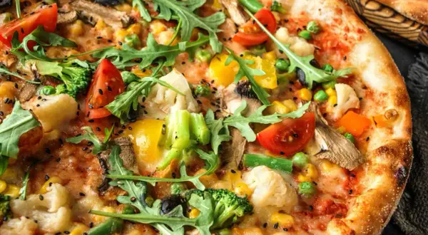 Apetyczna pizza bez mięsa z brokułami, pomidorkami, kukurydzą i rukolą.