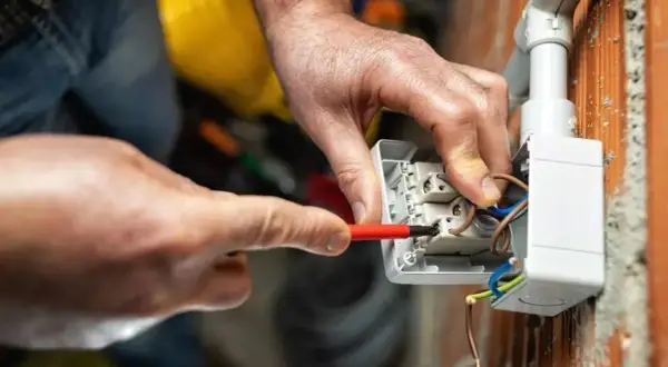 Elettricista collega cavi a una presa, mostrando le differenze tra i tipi di connessione.