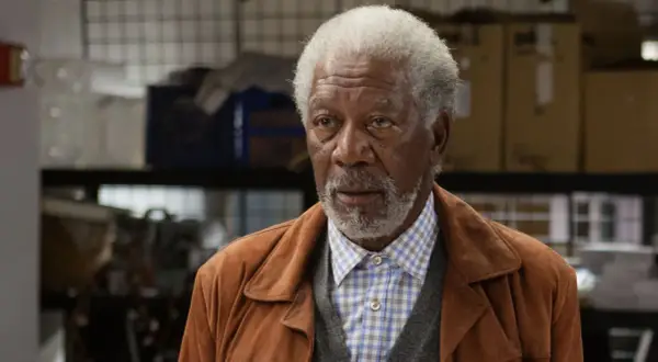Morgan Freeman w brązowej kurtce i kratowanej koszuli, jak z jego filmów.