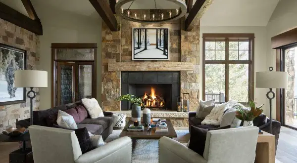 A cozy living room with a stone fireplace, exposed wooden beams, and plush seating embodies rustic interior design.