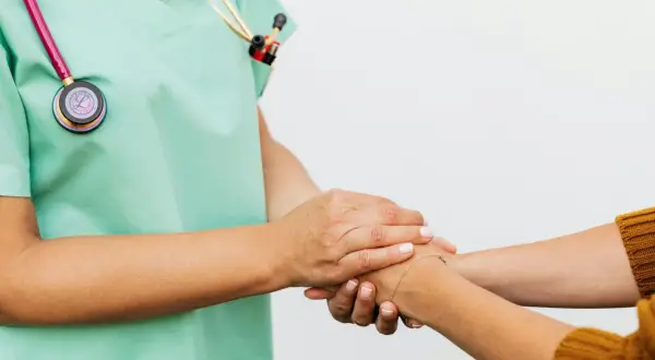 Un infermiere rassicura un paziente, superando la paura dei medici con un gesto di conforto.