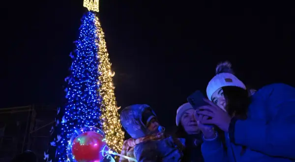 Choinka ozdobiona w barwach Ukrainy, ludzie robiący zdjęcia telefonami.