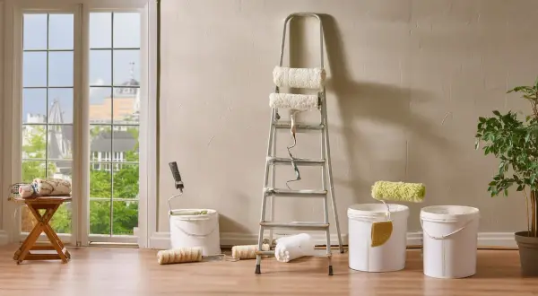 Préparation pour nettoyer mur intérieur crépi avant peinture : rouleaux, seaux et échelle sont prêts.