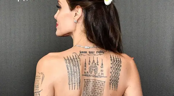 Angelina Jolie z tatuażem sak yant na plecach, przedstawiającym skomplikowane wzory i napisy.