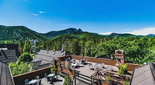 Taras hotelowy z widokiem na góry i lasy.
