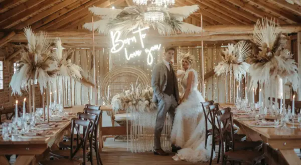 Eleganckie wesele w stodole: boho dekoracje z traw pampasowych, neon "Born to love you" i para młoda.