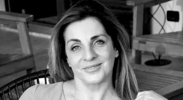 Ritratto in bianco e nero di una donna con capelli castani lunghi e mossi, occhi azzurri e un sorriso leggero. Sembra pensierosa, come se fosse andata a convivere ma non fosse felice.