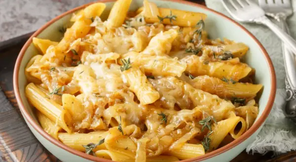 Penne z pysznym, karmelizowanym sosem cebulowym i roztopionym serem, udekorowane świeżym tymiankiem. Idealny sos do makaronu.